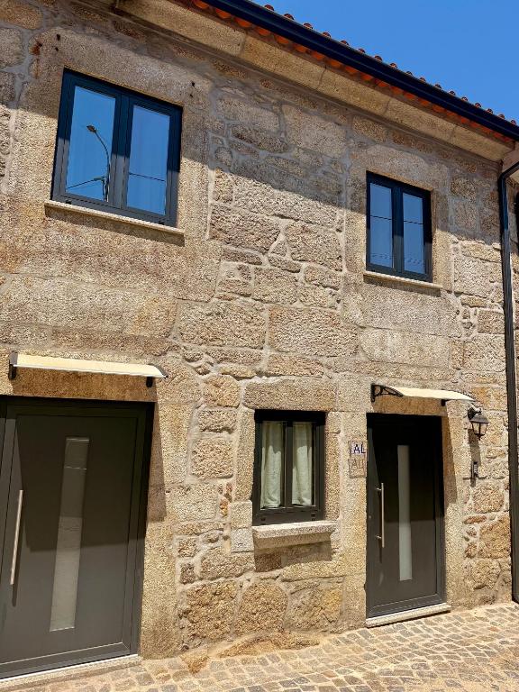 ein Steingebäude mit zwei Garagentoren und zwei Fenstern in der Unterkunft Recanto do Cávado in Barcelinhos