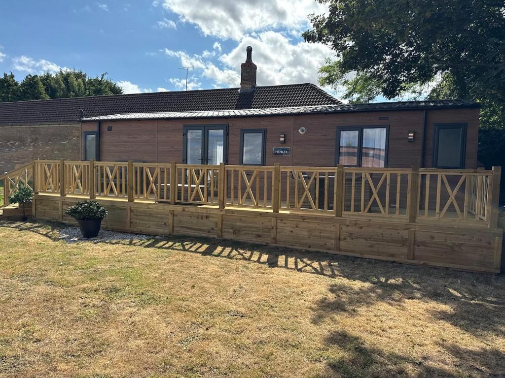 a house with a wooden fence in front of it at Luxury lodge Henley in Cherry Burton