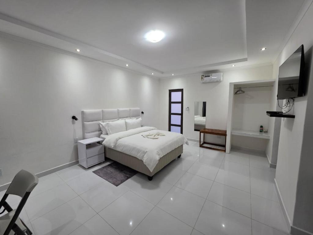 a white bedroom with a bed and a television at SADO Guesthouse in Katima Mulilo