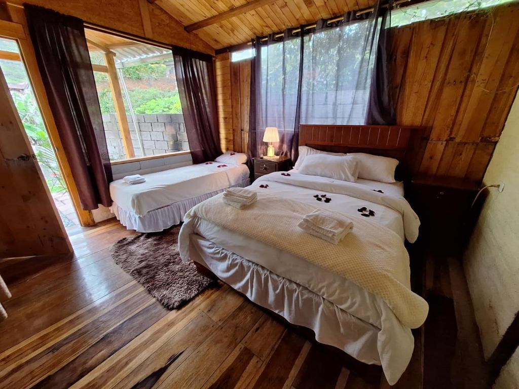 a bedroom with two beds and a window at Casa Refugio del Amanecer en Baños de Agua Santa in Lligua
