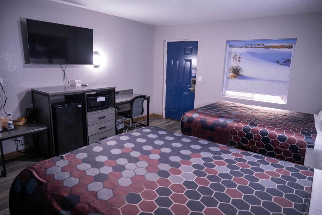 a hotel room with two beds and a desk and a television at Budget Inn in Alamogordo