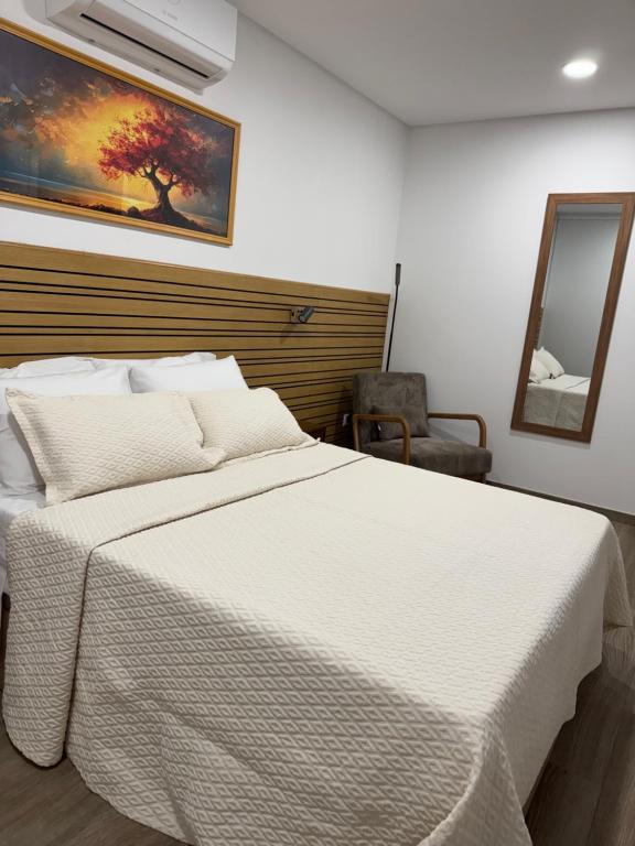 ein Schlafzimmer mit einem weißen Bett und einem Spiegel in der Unterkunft Malecón Do Azeite in Moura