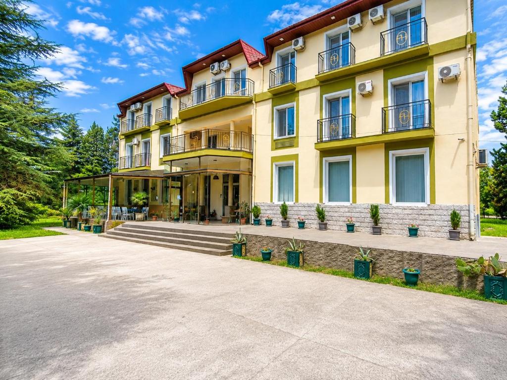 ein großes gelbes Gebäude mit Topfpflanzen davor in der Unterkunft Park Hotel Imeri kutaisi in Kutaissi
