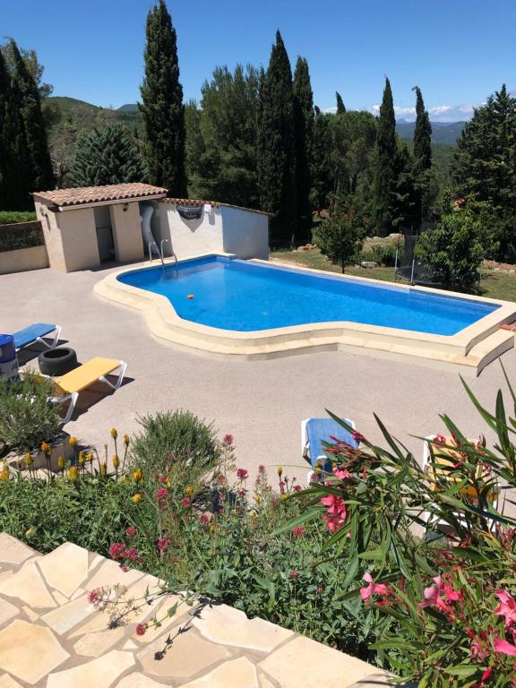 a large swimming pool in a yard with flowers at Gîte Apaisant in Llauro