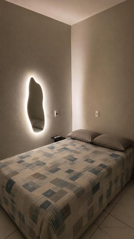 a bedroom with a bed with a head light on the wall at Studio Confortável no Centro com Garagem in Araquari