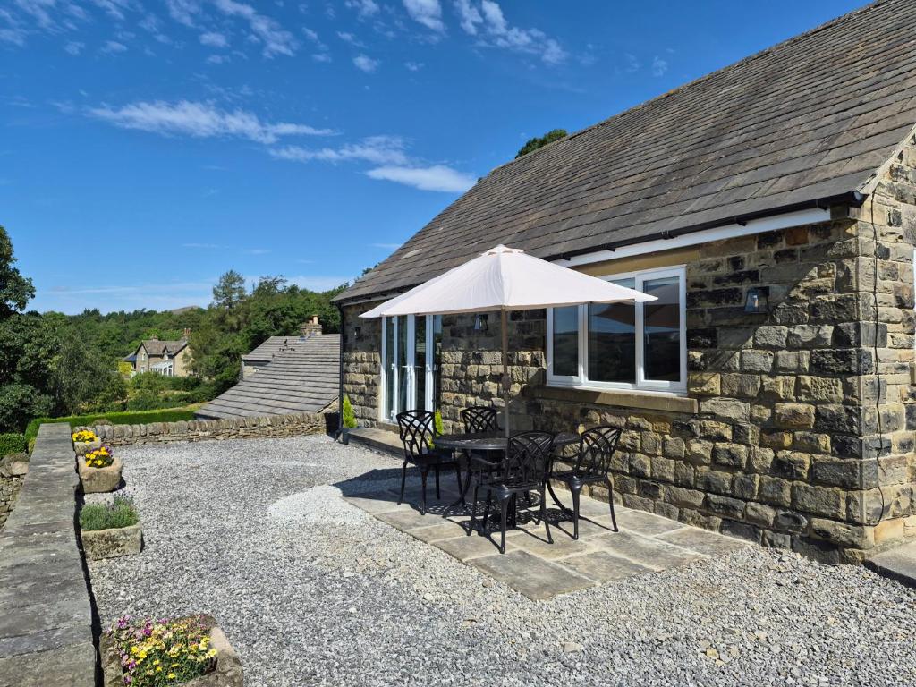 a stone house with a table and an umbrella at Thorn Tree Cottage in Hope