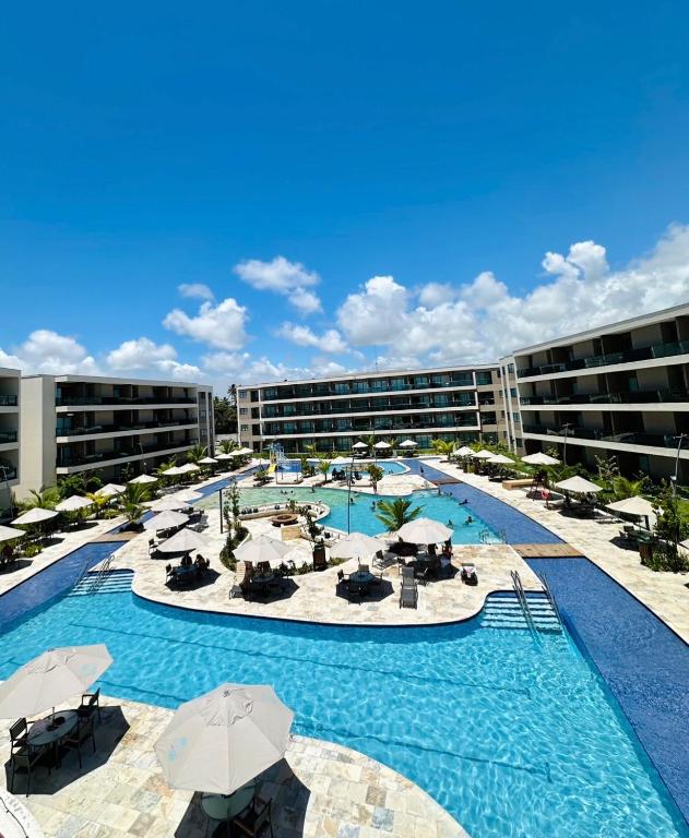 a large pool with chairs and umbrellas in a hotel at Resort de Luxo em Muro Alto - Porto de Galinhas in Ipojuca