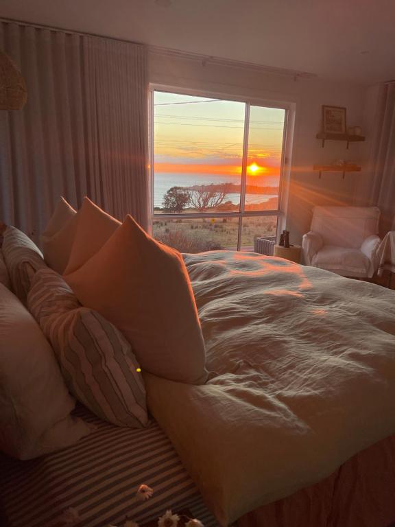 a bedroom with a bed and a window with the sunset at Travellers Rest Bicheno in Bicheno