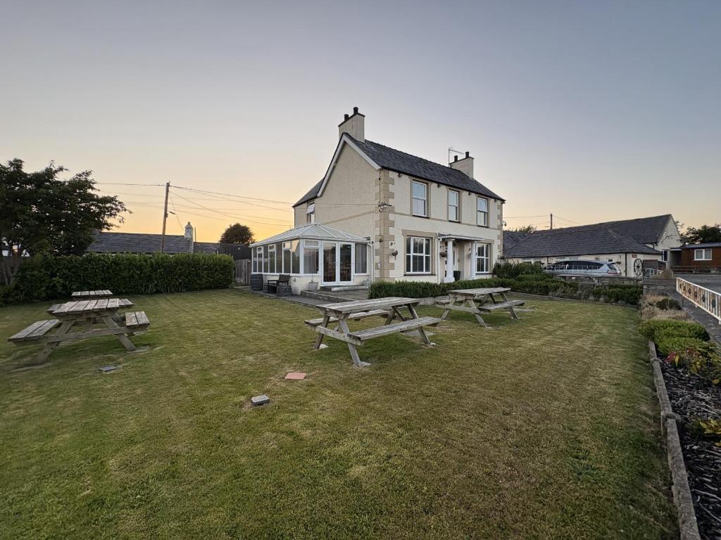 a white house with picnic tables in the yard at Taldrwst At Dwyran in Dwyran