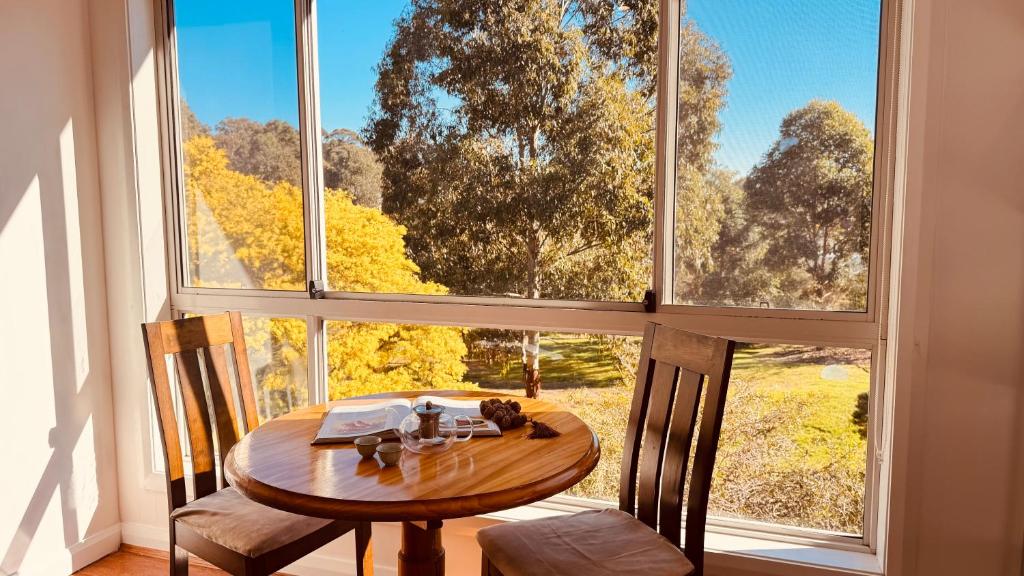 a table and chairs in a room with a large window at Golf Course Frontage House in Schofields