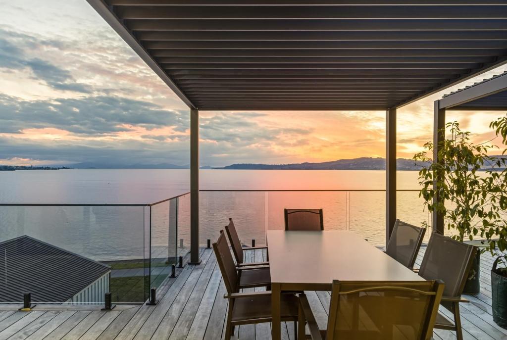 a table and chairs on a deck with a view of the water at Roam Taupo Upper Terrace Unit 3 - Spa Pool in Taupo
