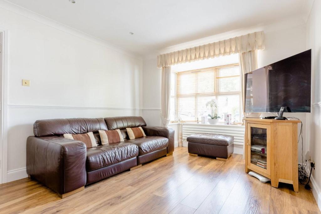a living room with a leather couch and a flat screen tv at Single Room with shared bathroom in Cheshunt