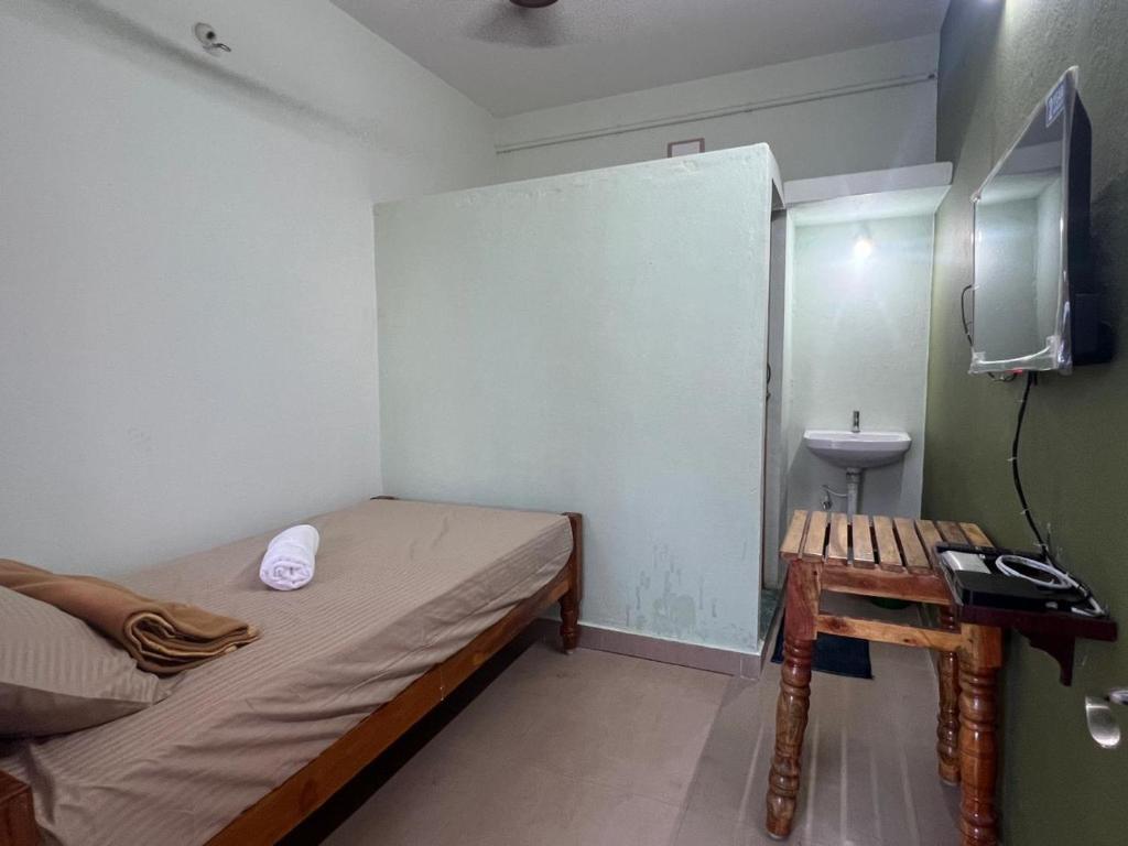 a small room with a bed and a sink at Vijay residency TVR in ThiruvÄrÅ«r