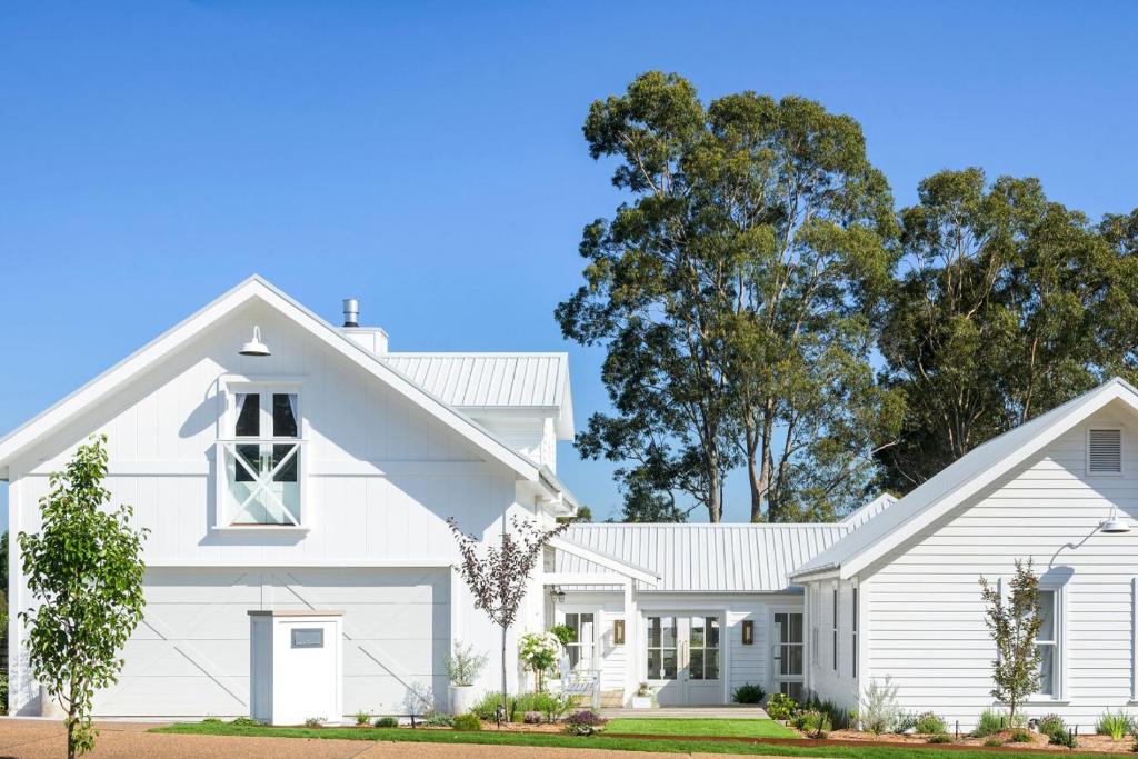 a white house with trees in the background at Farmhouse Hunter Valley in Pokolbin