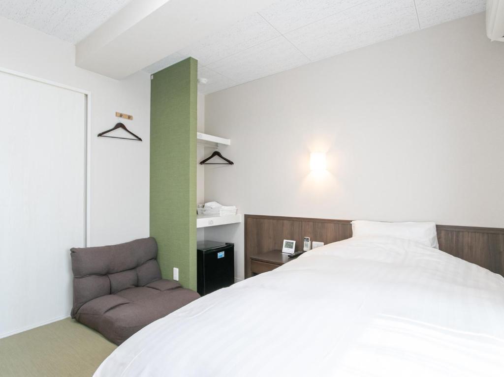 ein Schlafzimmer mit einem großen Bett und einem Stuhl in der Unterkunft HOTEL Calmplace in Kanda