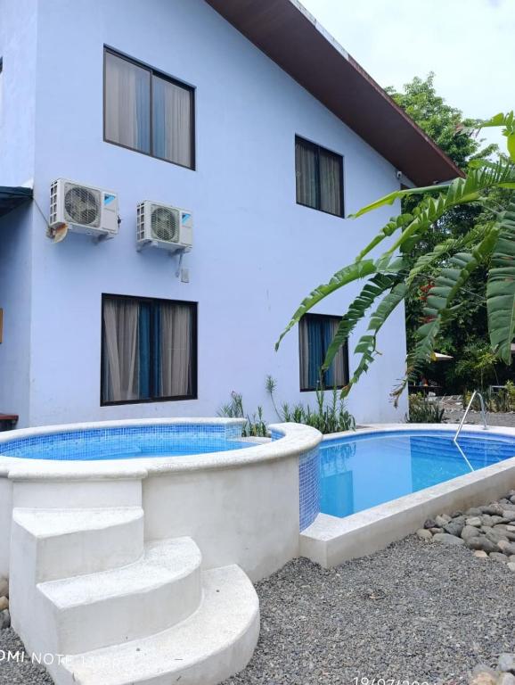 a villa with a swimming pool in front of a building at TULIN AZUL -Cabina familiar con piscina y cocina equipada, cerca de Jaco- in Tulín