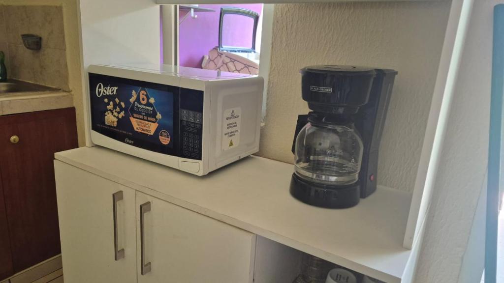 a coffee maker and a microwave on a shelf in a kitchen at Residencial Acropolis in Sonsonate