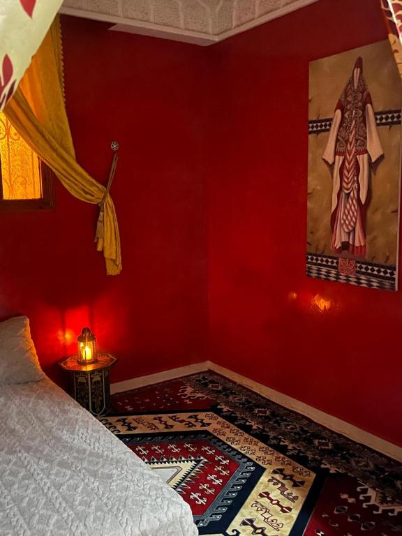 a red room with a bed and a painting on the wall at Tafoukt 2 in Kasba Aït Youdi