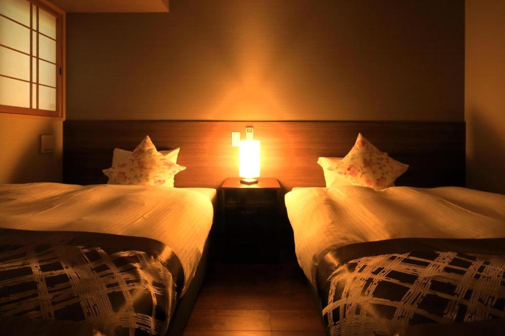 two beds in a room with a lamp between them at Take no Oyado in Kyoto