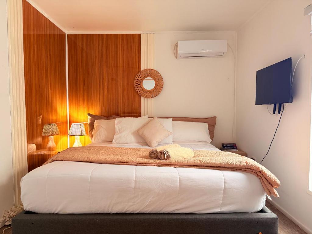 a bedroom with a large bed with white sheets and pillows at Casa Withe opción jacuzzi estadía villa alemana in Villa Alemana