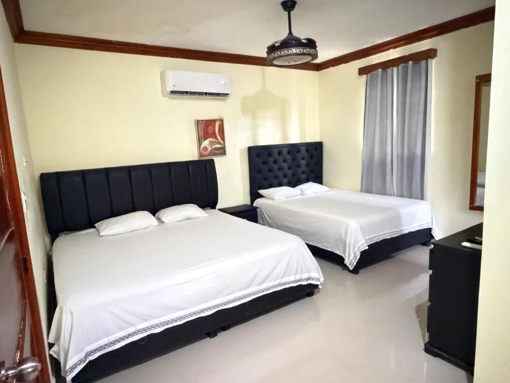 two beds in a room with white sheets at Aparta hotel doble in Higuey
