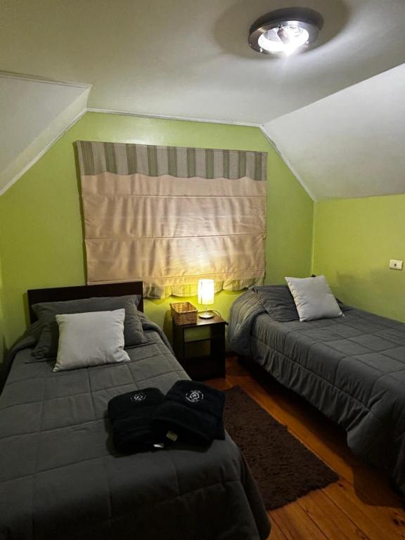 two beds in a room with green walls at Hostal el valle in Angol