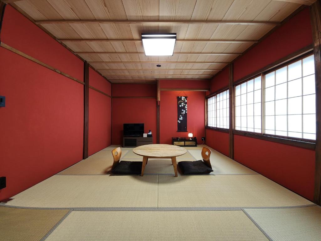 a room with red walls and a table and chairs at 龍助25ANNEX Ryusuke25ANNEX in Komatsu
