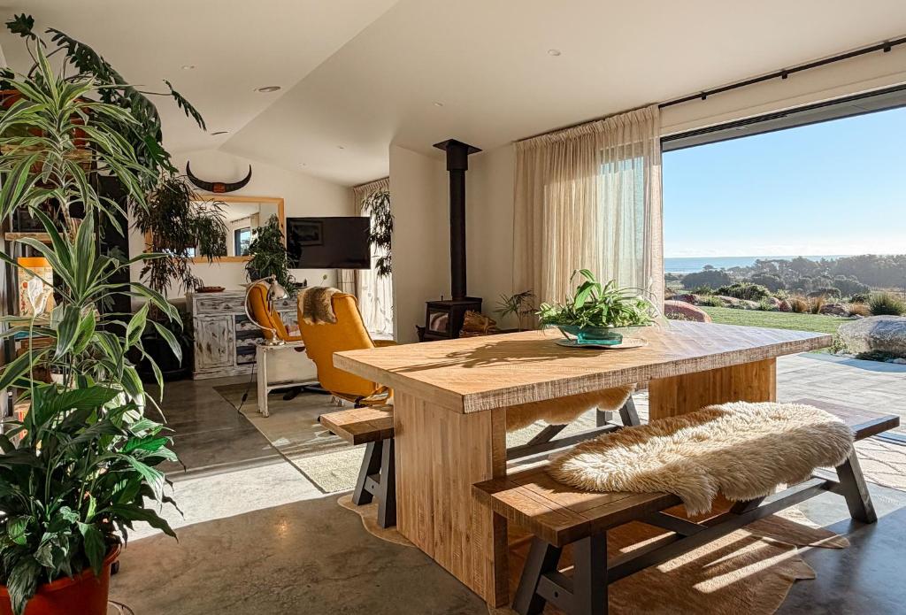 a living room with a wooden table and a large window at The Highland - Sunset Ridge in Ruatapu