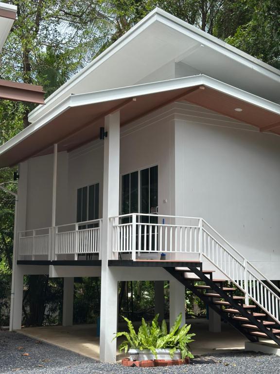 a white house with a porch and a balcony at The Summer Cozy Cottage 2 in Haad Chao Phao