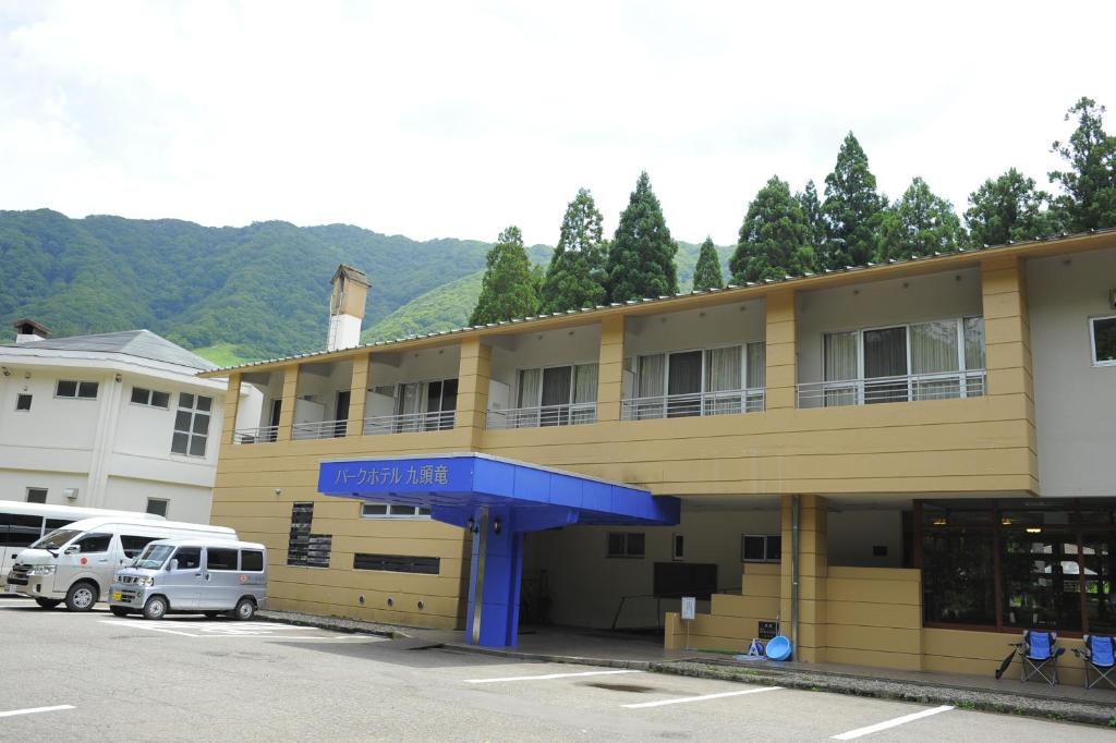 a yellow building with a parking lot in front of it at パークホテル九頭竜 in Ōno