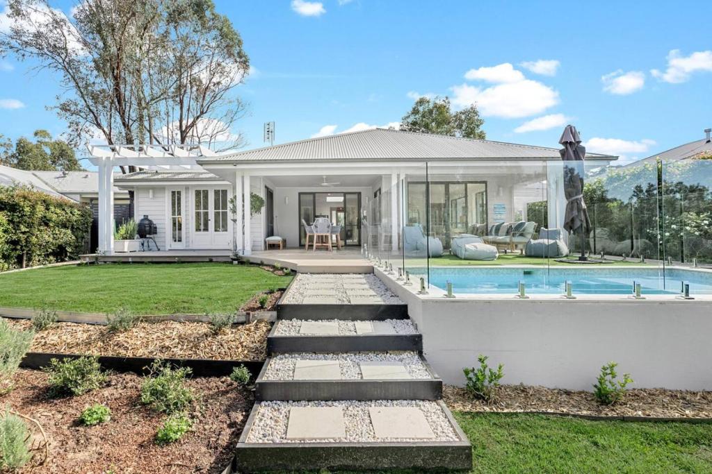a house with a swimming pool and a yard at Whitepepper Cottage in Pokolbin