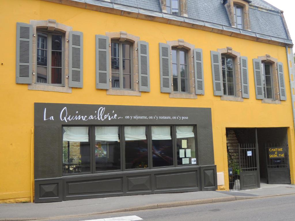 um edifício amarelo com uma frente de loja com janelas em La Quincaillerie em Audierne