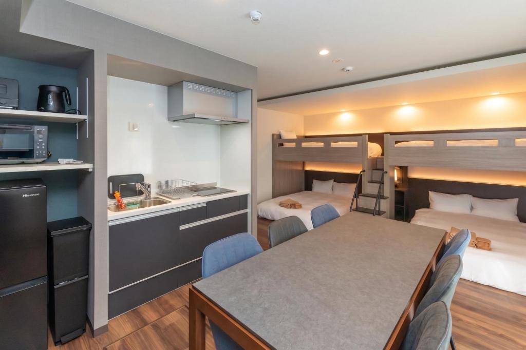 a room with a dining table and a kitchen with bunk beds at ReLA Minami-Nagareyama in Nagareyama