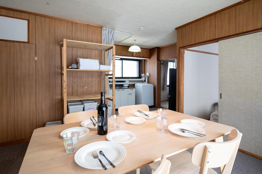 a dining room table with white plates and a bottle of wine at c Furano A in Furano