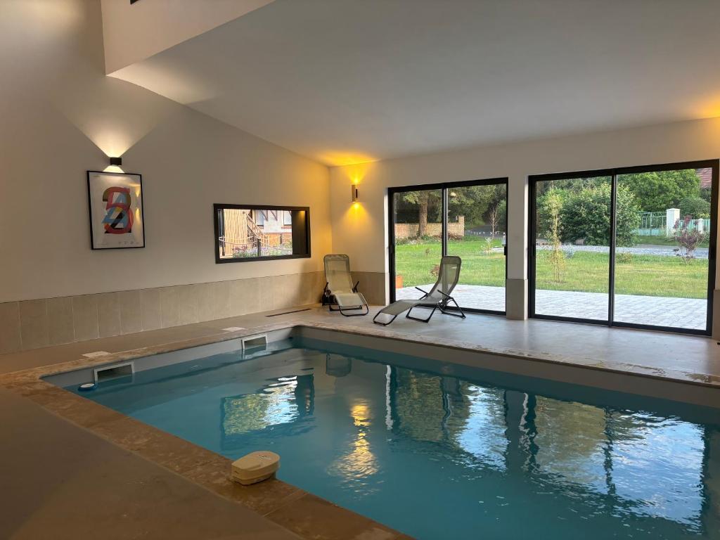 a swimming pool with two chairs in a house at Sillage in Machiel