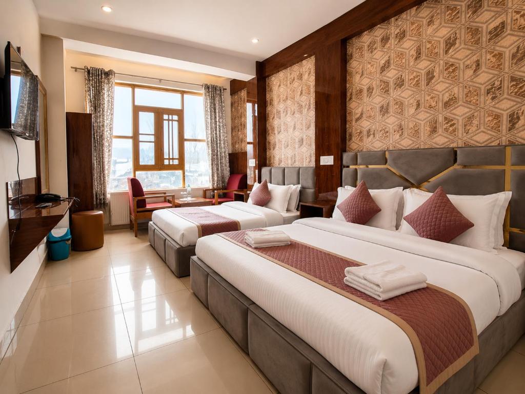 a hotel room with two beds and a television at Gulmarg GS Residency Hotel in Gulmarg