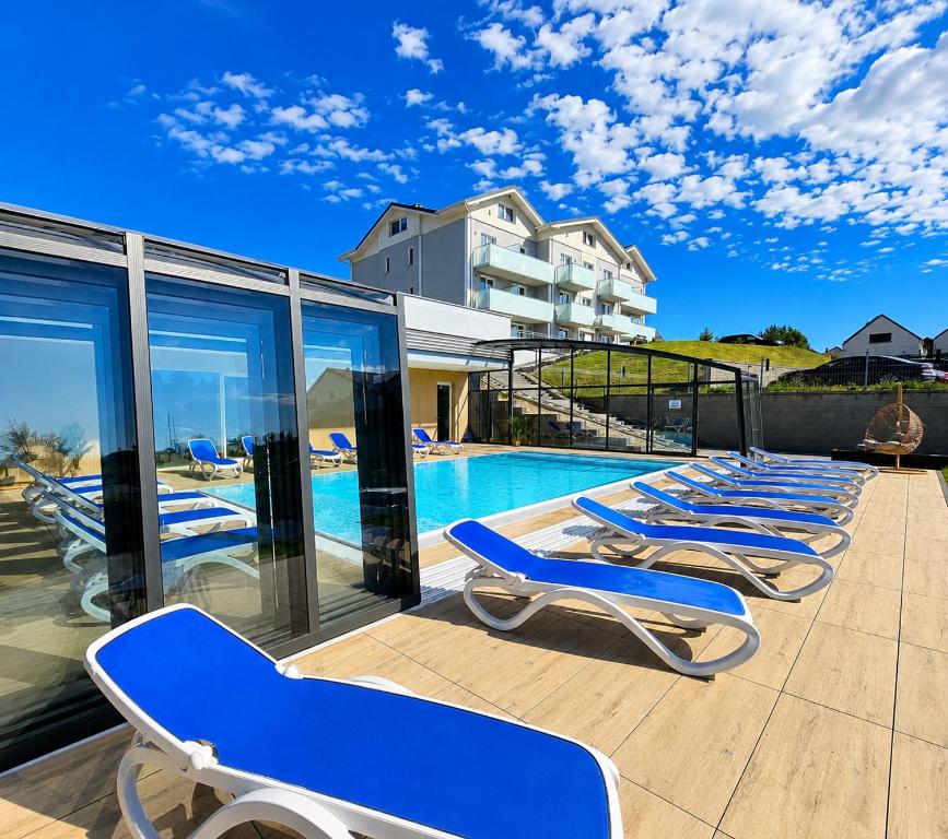 a row of blue lounge chairs next to a swimming pool at BELMAR Park Resort in Władysławowo