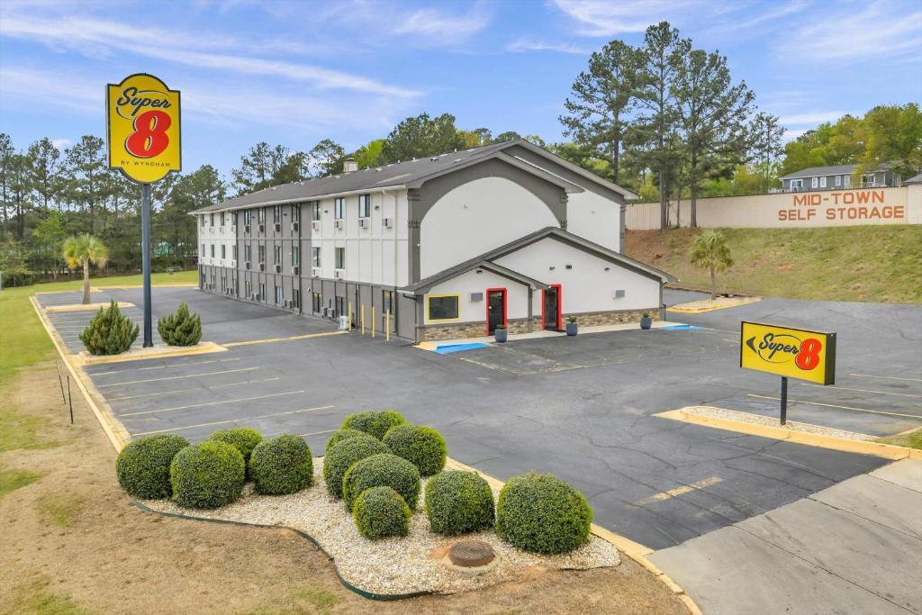a building with a sign in a parking lot at Super 8 by Wyndham Warner Robins in Warner Robins