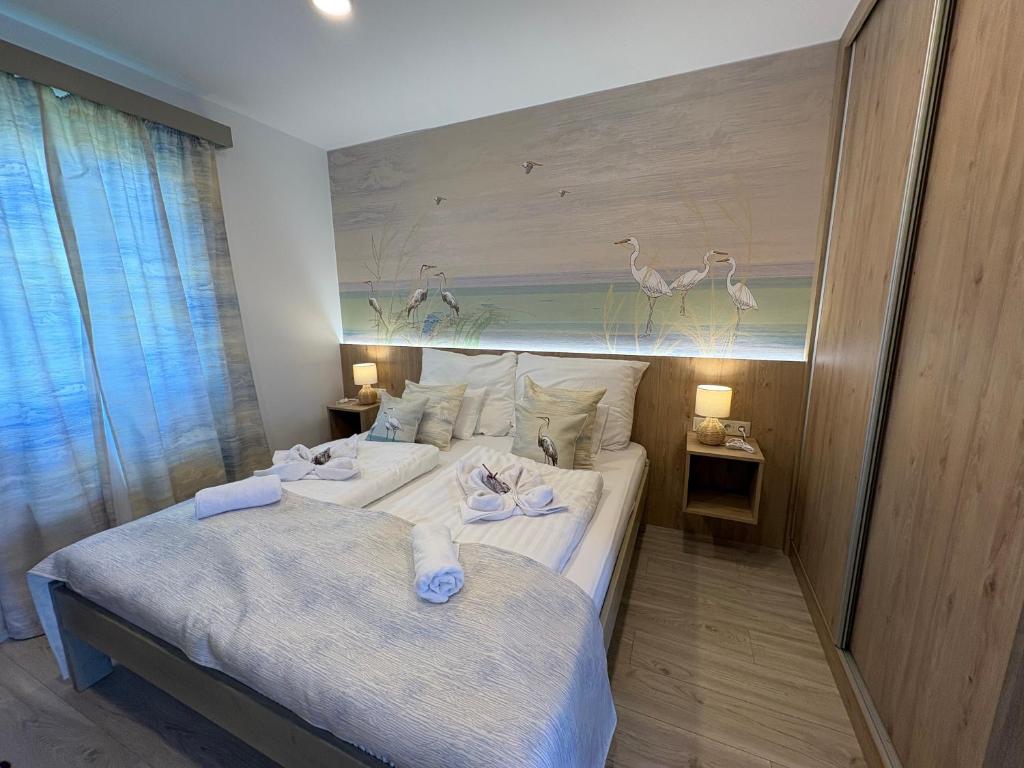 a bedroom with two beds and a painting of birds at Levendula Apartman in Buzsák