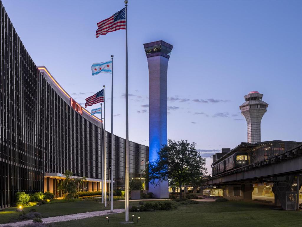 two towers with american flags in front of a building at Hilton Chicago O'Hare Airport in Rosemont