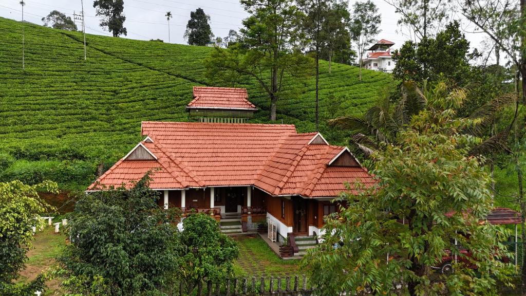 a house with an orange roof on a hill at Traditional Villa Munnar in Anachal
