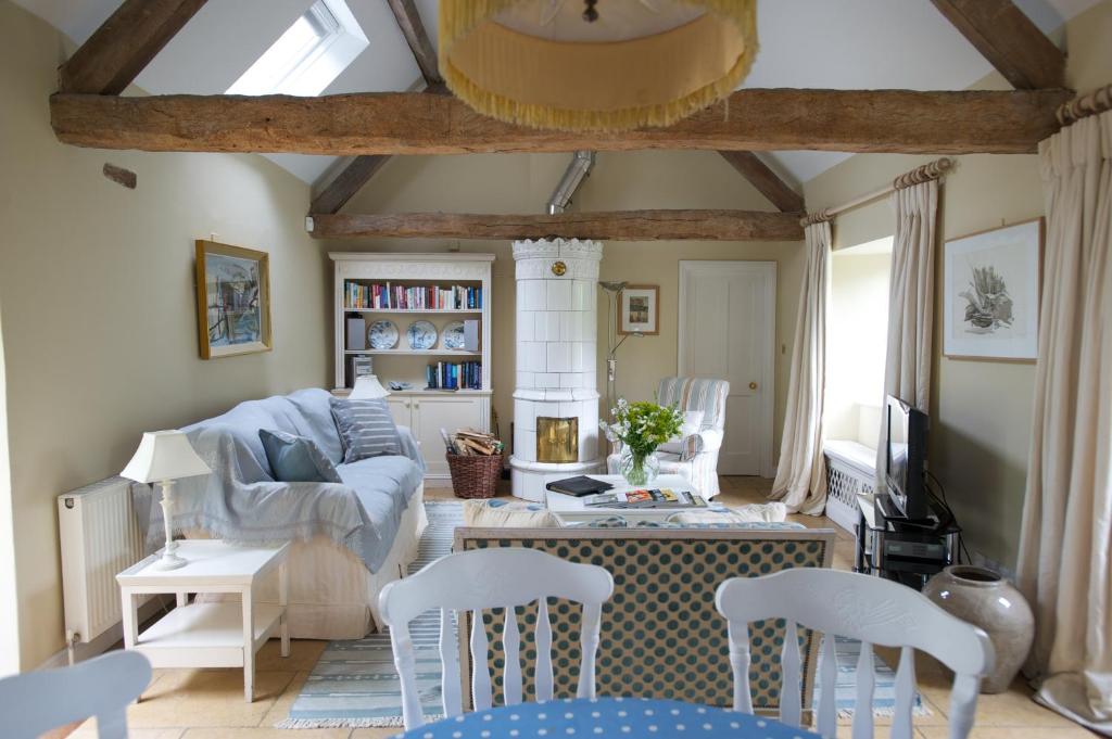 a living room with white chairs and a couch at Shipton Cottage in Bruern