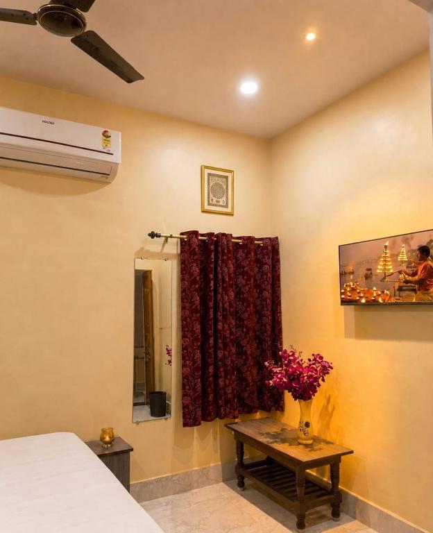 a bedroom with a bed and a vase of flowers on a table at Ratnadeep Palace - Near Kashi Vishwanath Temple & Ghats in Varanasi