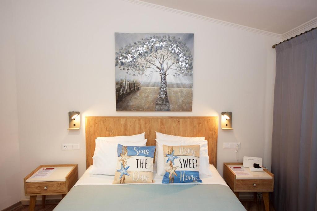 a bedroom with a bed with a painting on the wall at Nina's House by CorfuEscapes in Doukádes