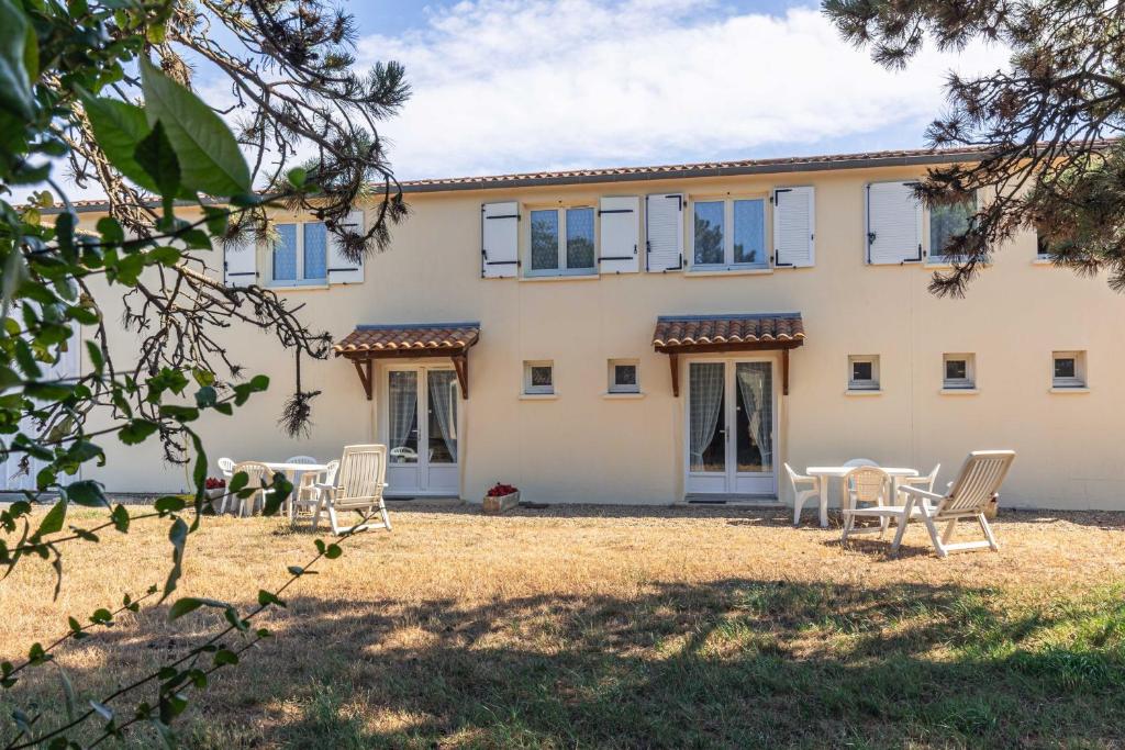a house with chairs and tables in front of it at Duplex N°1 - Résidence Balnéaire in Le Port-des-Barques