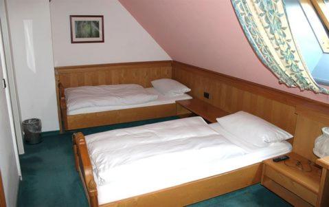 two twin beds in a room with a window at Hotel B&S in Waghäusel