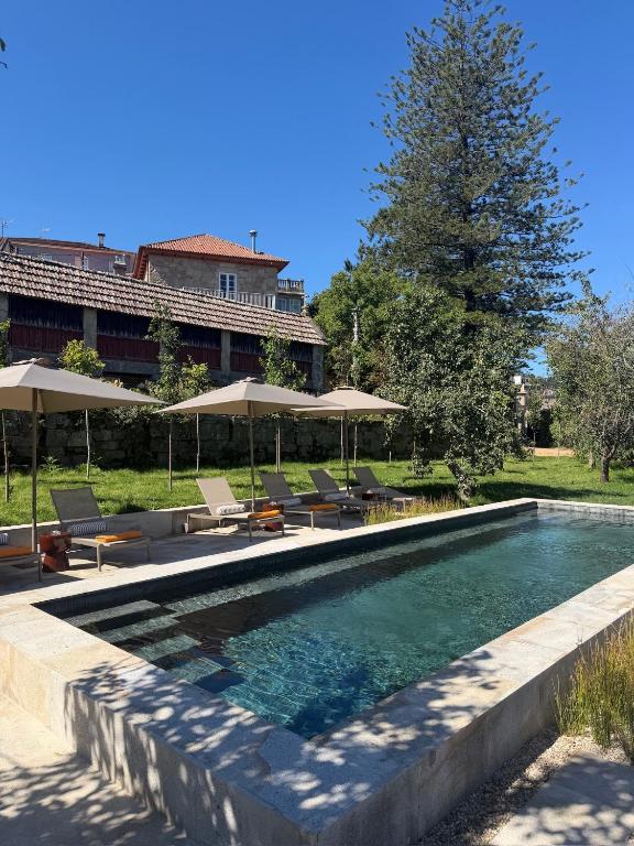 a swimming pool with chairs and umbrellas at VILLA LORES Adults Only Retreat near Sanxenxo & O Grove in Lores