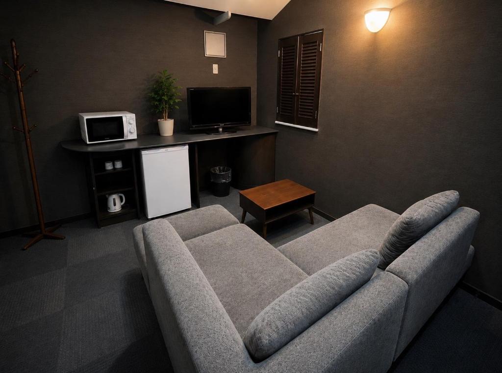 a living room with a couch and a tv at ホテルwith宮崎 in Miyazaki
