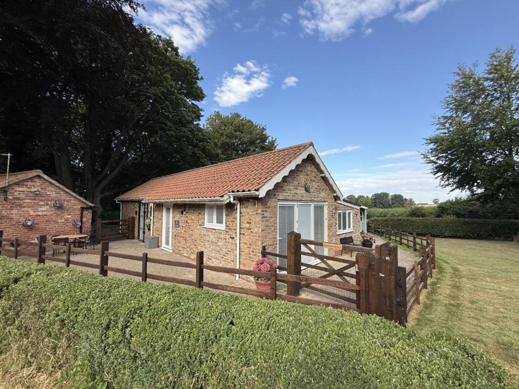 a small brick house with a wooden fence at Crossways Sycamore in Grimsby