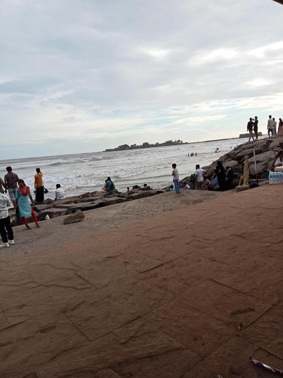 a group of people standing on a beach at Grantley -Beach hotel Alibag in Alībāg